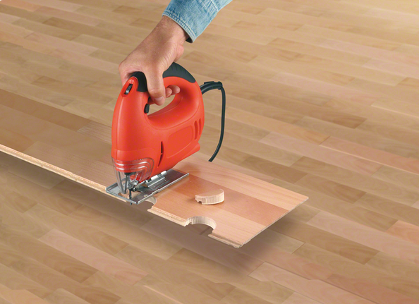 Gergaji ukir memotong lekukan lengkung pada papan lantai laminasi.