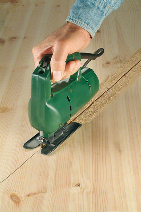 Seseorang mengarahkan gergaji ukir untuk memotong garis lurus melalui papan kayu.