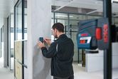 Seseorang mengarahkan penerima laser pada pilar beton di kantor modern.