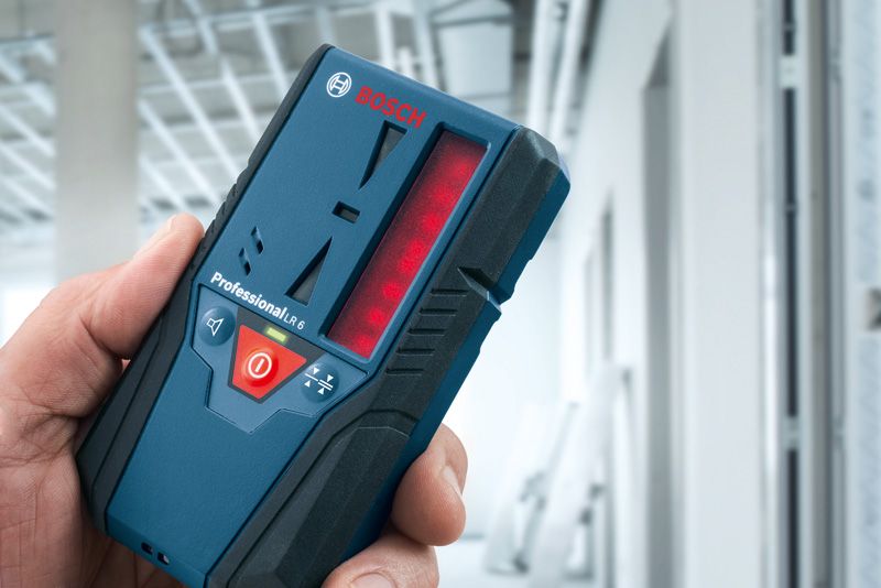 Seseorang memegang penerima laser di gedung yang sedang dibangun.