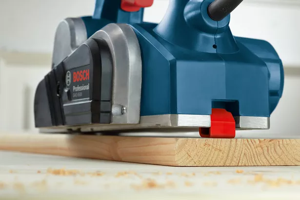 GHO 6500 Planer listrik menghaluskan papan kayu di meja bengkel.