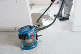 Seseorang menggunakan penyedot debu tanpa kabel untuk membersihkan cairan dari lantai beton.