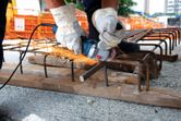 Seseorang yang mengenakan perlengkapan keselamatan menggunakan penggiling sudut untuk memotong tulangan beton di lokasi konstruksi.