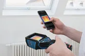 Seseorang menggunakan kamera termal dan telepon pintar untuk melihat gambar termal di dalam ruangan.