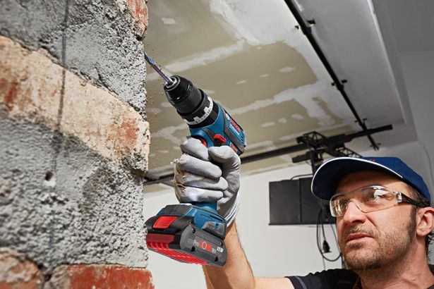 ProCORE18V 4.0Ah Seseorang yang mengenakan peralatan keselamatan mengebor dinding bata dengan bor listrik tanpa kabel.