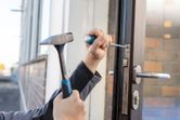 Orang yang menggunakan palu dan obeng untuk memasang mekanisme kunci pintu.
