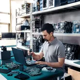 Seseorang menggunakan obeng tanpa kabel untuk merakit komponen elektronik di meja kerja.