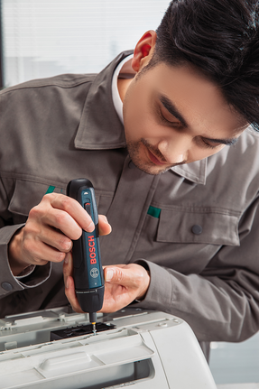 Seseorang sedang merakit mesin kantor menggunakan obeng tanpa kabel.