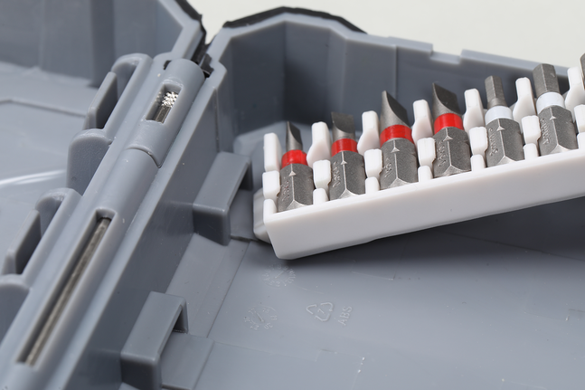 Berbagai macam mata obeng tersusun rapi dalam wadah plastik di dalam kotak perkakas berwarna abu-abu.