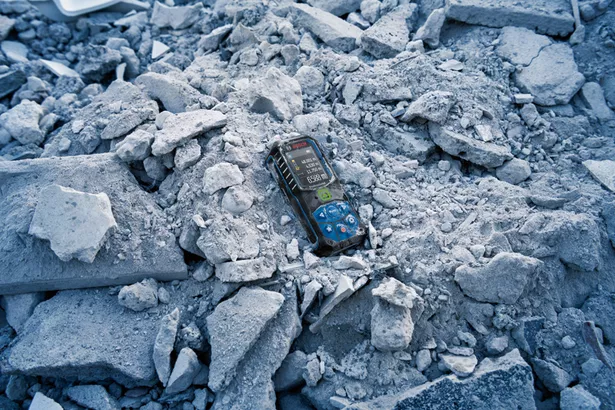 GLM 50-23 G Alat pengukur laser diletakkan di atas tumpukan puing beton yang pecah.