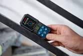 Seseorang mengukur sudut pada balok logam menggunakan pengukur laser.