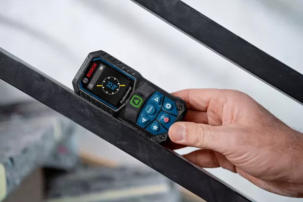 GLM 50-23 G Seseorang mengukur sudut pada balok logam menggunakan pengukur laser.