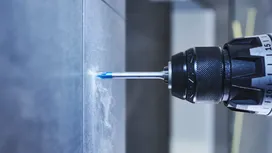 Bor listrik membuat lubang di dinding keramik.