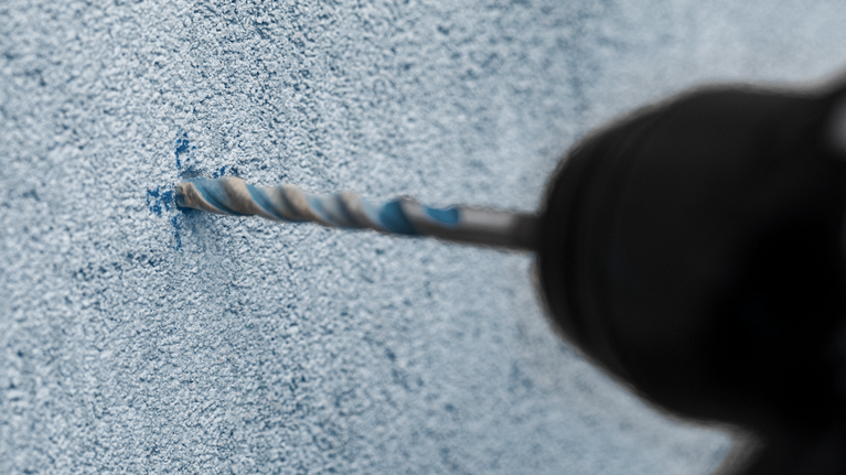 Bor palu putar menembus dinding beton.