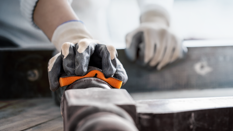 Orang yang mengenakan perlengkapan keselamatan mencengkeram pipa logam untuk penyelarasan.