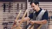 Seseorang mengamankan potongan kayu menggunakan obeng tanpa kabel di bengkel.
