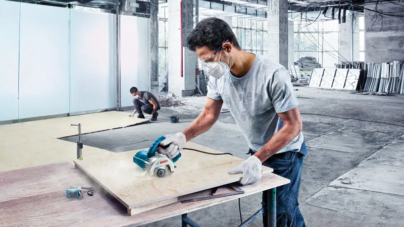 Pemotong ubin berlian Bosch GDC 140 sedang digunakan di lokasi kerja.