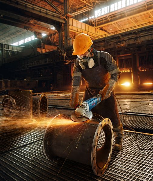 Pekerja menggiling pipa logam.