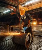 Pekerja menggiling pipa logam.