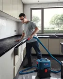 Seseorang yang mengenakan peralatan keselamatan menyedot debu dapur dengan ekstraktor basah dan kering.