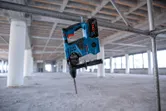 Palu putar tanpa kabel tergantung pada pipa logam di lokasi konstruksi yang belum selesai.