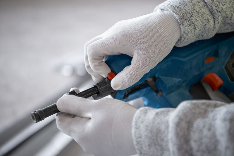 Orang yang mengenakan perlengkapan keselamatan sedang menyetel paku beton tanpa kabel.