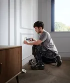 Seseorang memasang penutup stopkontak listrik dengan obeng tanpa kabel.