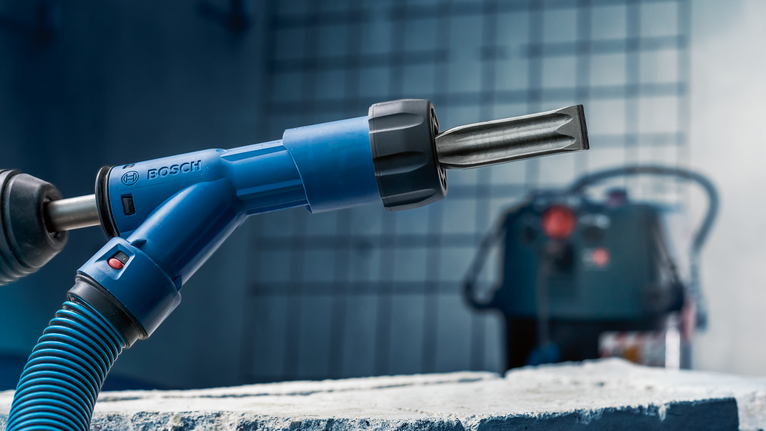 Palu putar dengan pahat yang diposisikan di atas balok beton kasar.