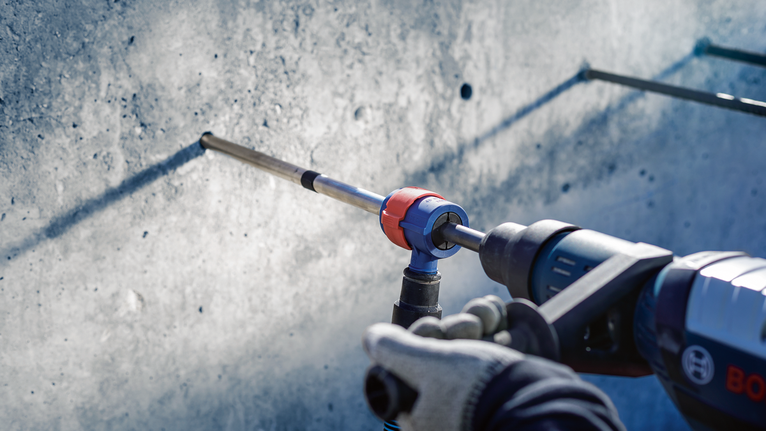 Orang yang mengenakan peralatan keselamatan mengebor dinding beton.