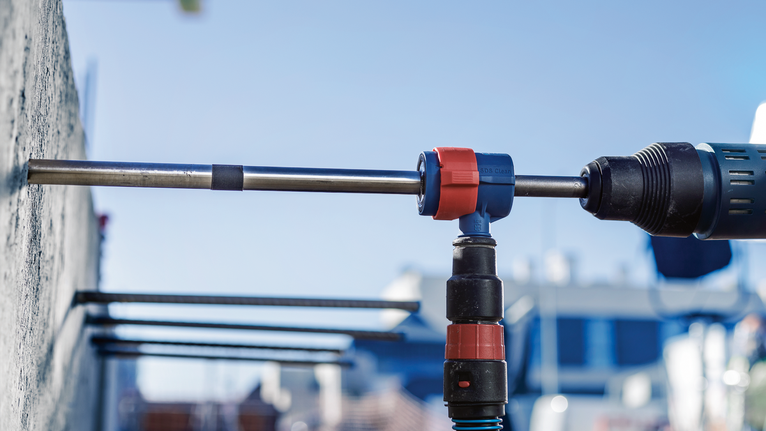 Pengeboran palu putar untuk melubangi dinding beton di luar ruangan.