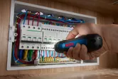 Orang menggunakan obeng tanpa kabel untuk mengencangkan sekrup pada panel listrik.