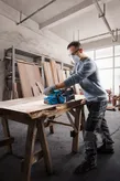 Mesin pengamplas sabuk Bosch GBS 750 menghaluskan papan kayu.