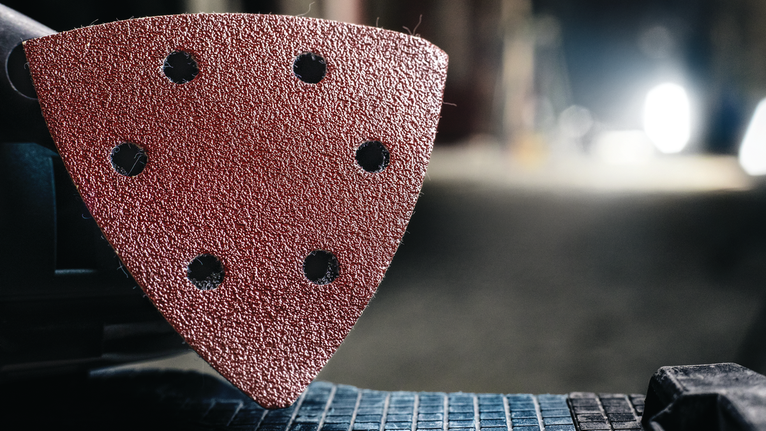 Tampilan detail bantalan pengamplasan segitiga yang terpasang pada perkakas listrik.