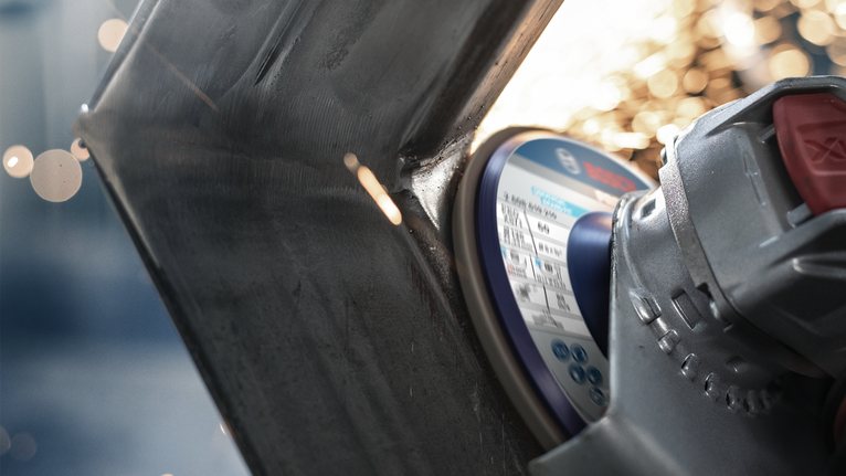 Penggiling sudut memotong logam, percikan api beterbangan dari titik kontak.