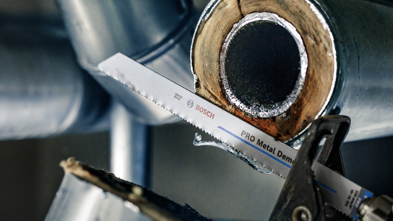 Mata gergaji bolak-balik yang memotong pipa logam dalam lingkungan industri.