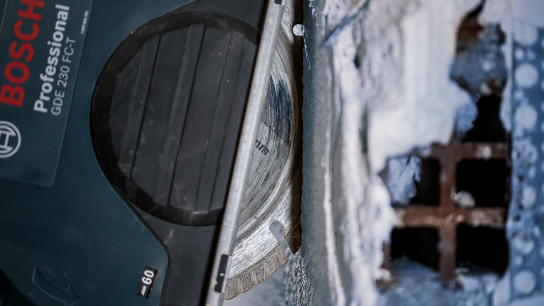 Mata gergaji berlian memotong beton di dekat jeruji logam.