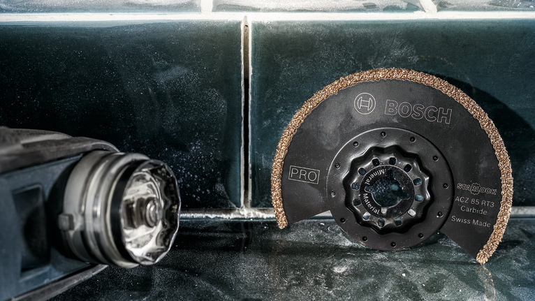 Mata gergaji karbida bundar diletakkan pada permukaan ubin di samping perkakas listrik.
