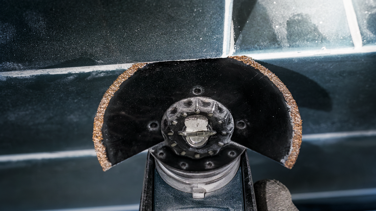 Alat pemotong dengan bilah abrasif yang aus memotong ubin keramik.