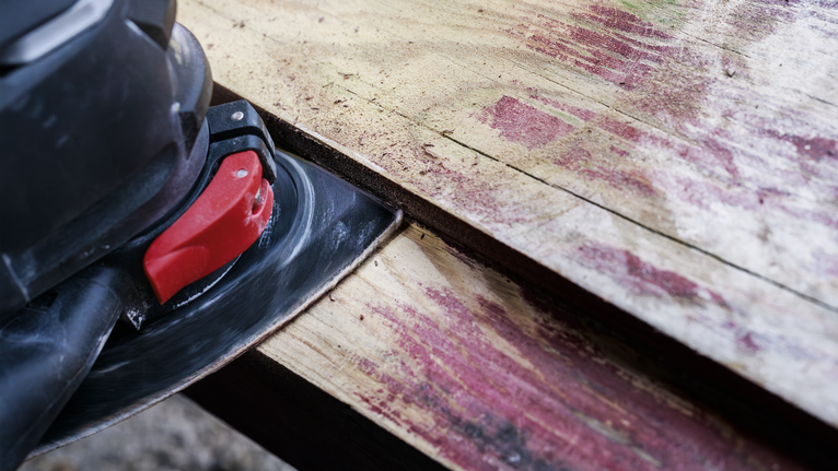 Mesin pengamplas listrik menghaluskan papan kayu yang lapuk.