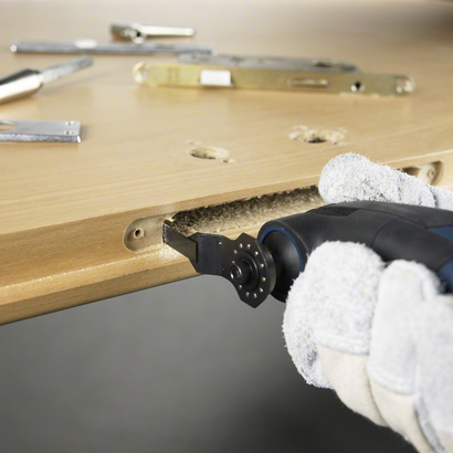 Object #200045996: LR_Allrounder-008627 Orang yang mengenakan perlengkapan keselamatan menggunakan alat serbaguna untuk memotong celah persegi panjang pada pintu kayu.