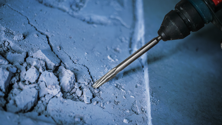 Palu putar yang memecah permukaan beton.