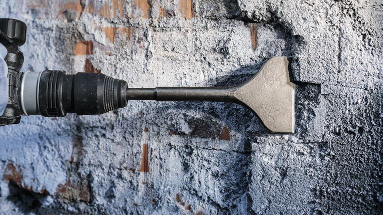 Pahat palu yang memecahkan dinding beton dalam proses pembongkaran.