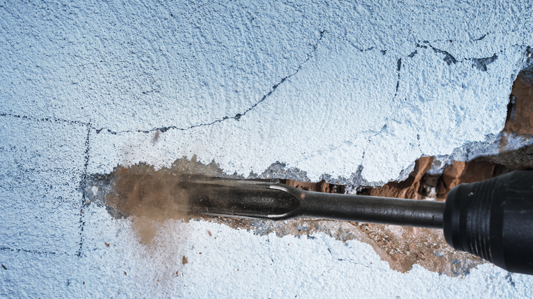 Palu putar memahat alur pada dinding yang diplester.