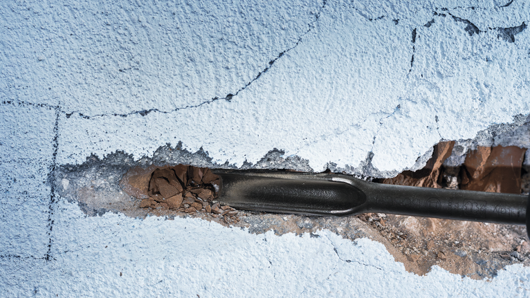 Alat pahat yang memecahkan plester pada dinding yang dicat.