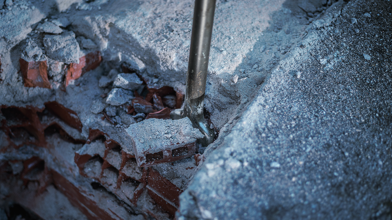 Pahat menembus beton dan puing-puing bata.