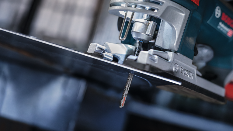 Gergaji ukir mengiris lembaran logam di bengkel.