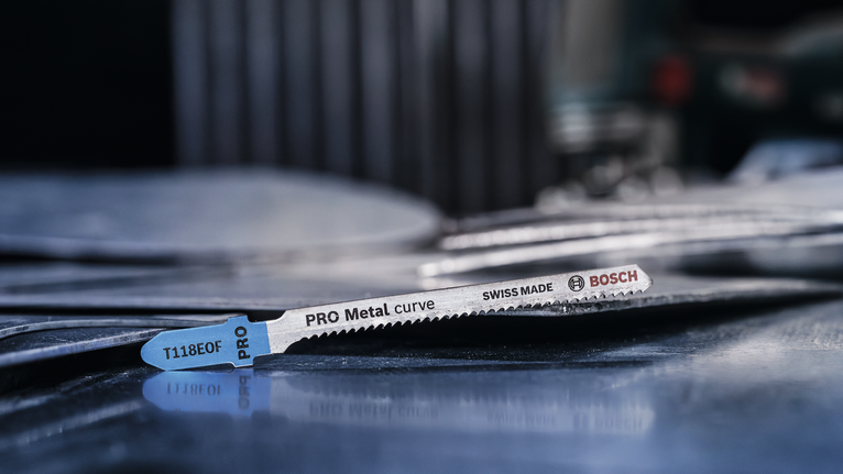 Mata gergaji logam diletakkan pada tumpukan lembaran logam di bengkel.