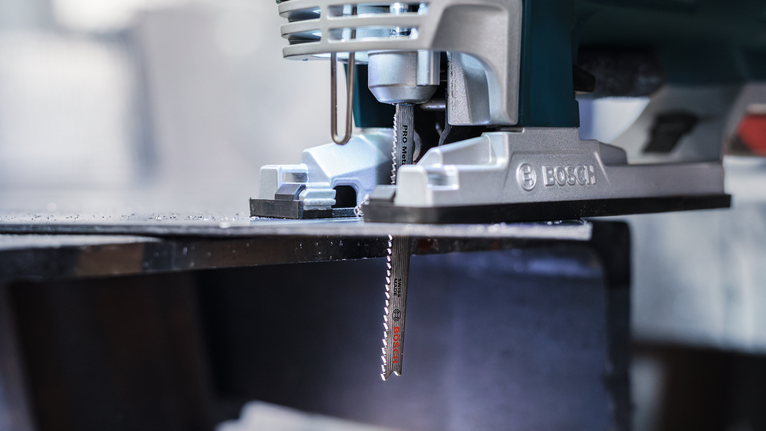 Gergaji ukir memotong lembaran logam di bengkel.