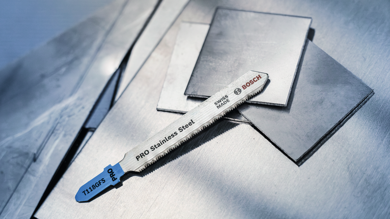 Mata gergaji ukir untuk baja tahan karat diletakkan di atas lembaran logam datar.