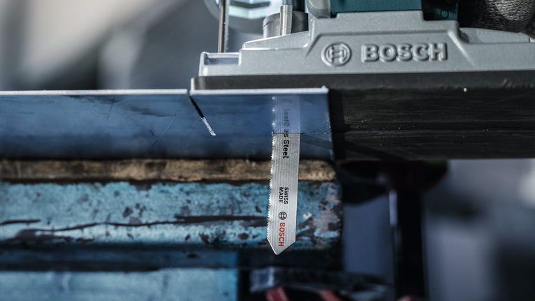 Gergaji ukir memotong lembaran logam di bengkel.